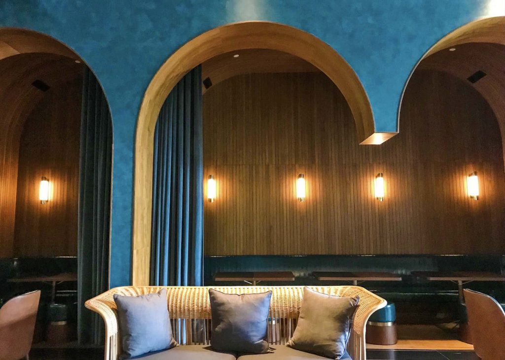 Intriguing arches, teal walls and wood tie together the art deco-inspired Origin Bar